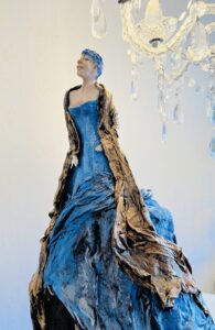 Kopf und Körperaus Ton, Kleid geiten Stoff über, Blau und Braun mit Goldglitzer, Weiblich , Faltenwurf Glitzer und Gesicht macht das Kunstwerk perfekt